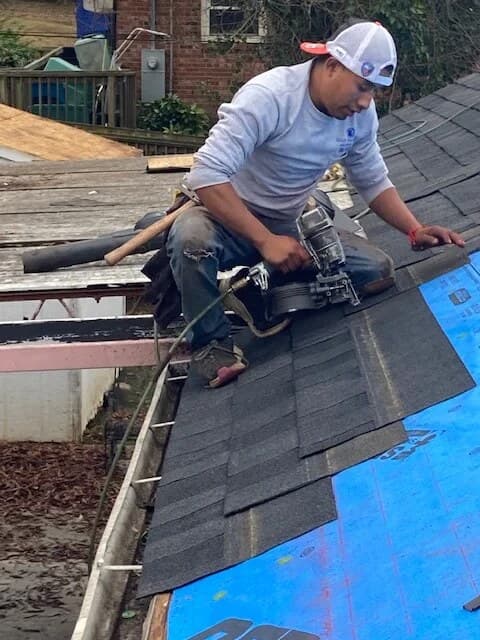 Rhody Roofing roofer nailing new architectural shingles over synthetic underlayment